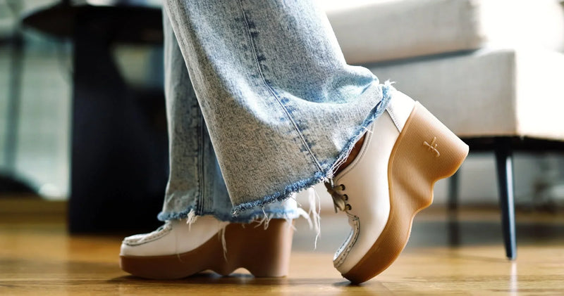 Woman wearing white platform shoes with cropped jeans while walking indoors.
